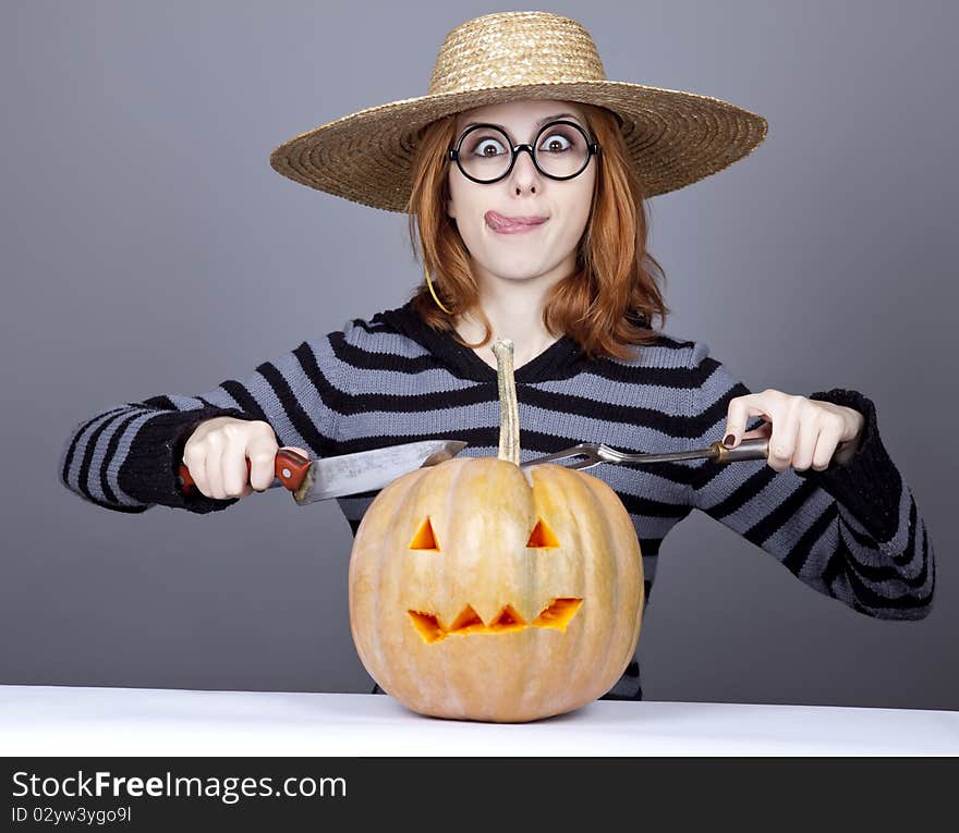 Funny girl in cap try to eat a pumpkin.