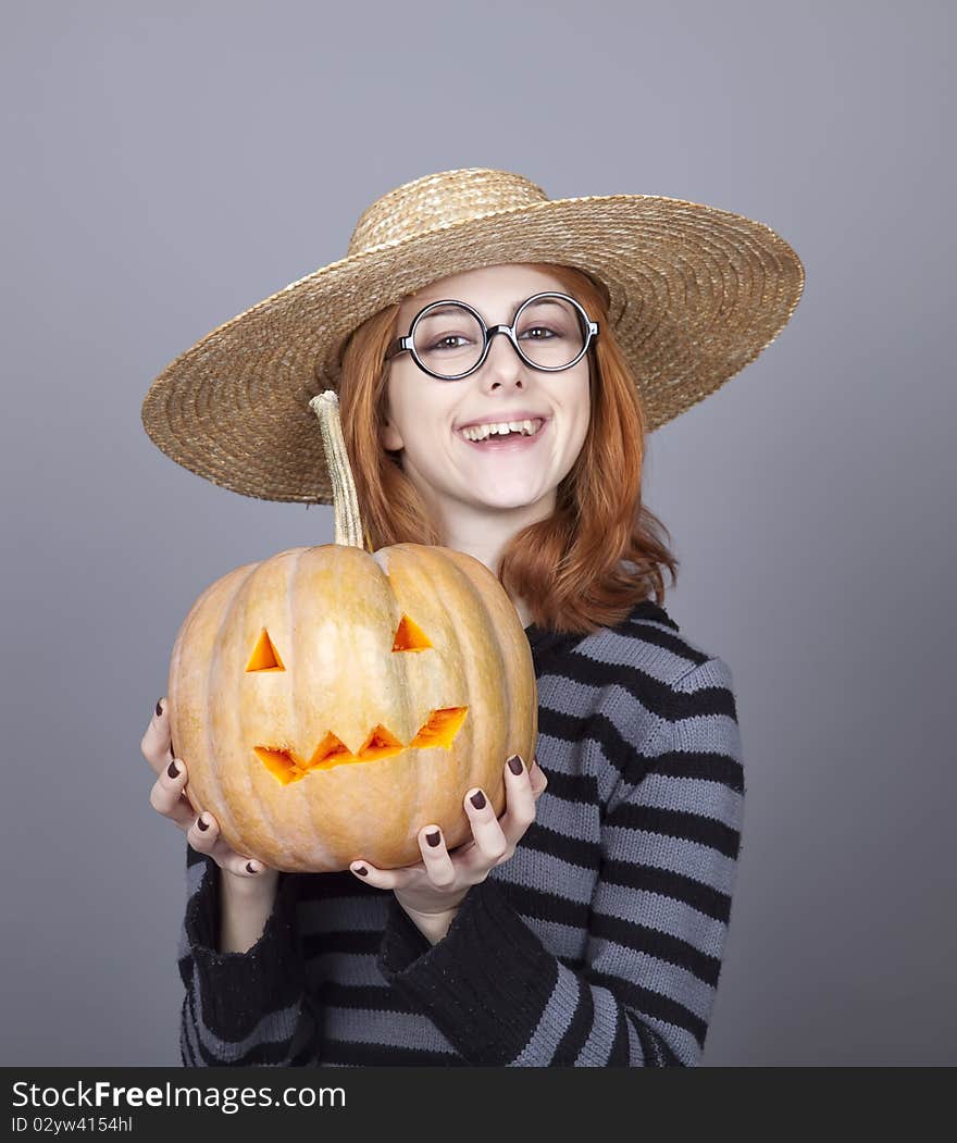 Funny girl in cap showing pumpkin. Studio shot.