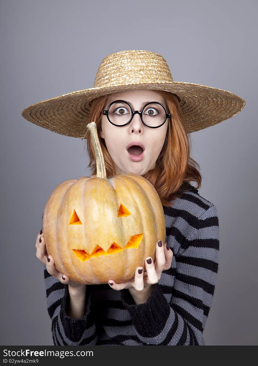 Funny girl in cap showing pumpkin.