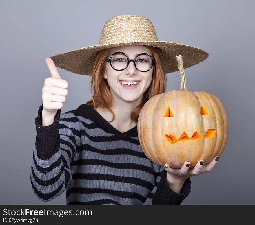 Funny girl in cap showing pumpkin. Studio shot.