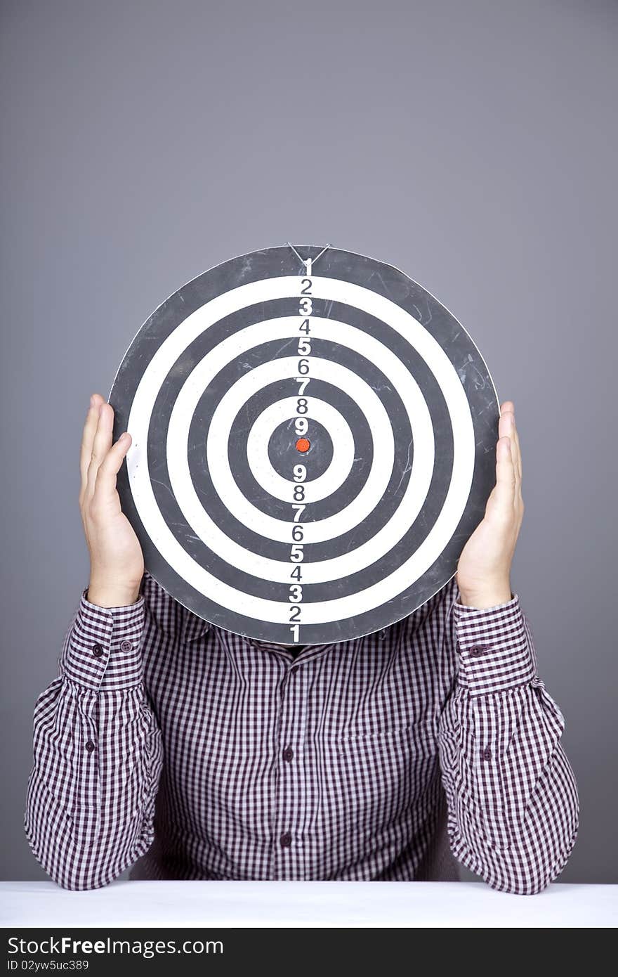 Boy with dartboard in place of head. Studio shot.