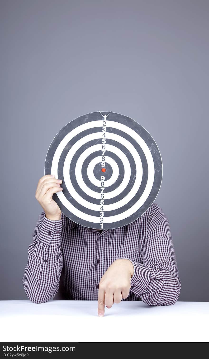 Boy with dartboard in place of head. Studio shot.