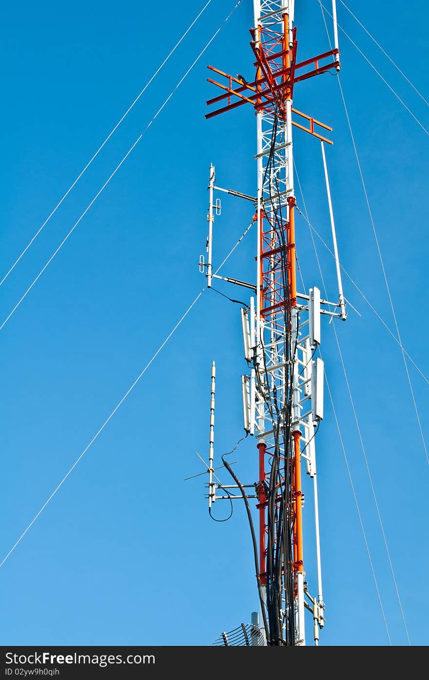 Tower of communications with antennas silhouetted against blue sky in town. Tower of communications with antennas silhouetted against blue sky in town.