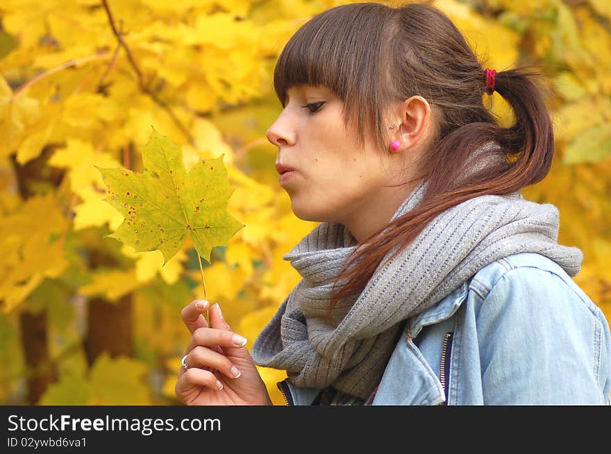 A girl holding a maple leaf in autumn scenery. A girl holding a maple leaf in autumn scenery