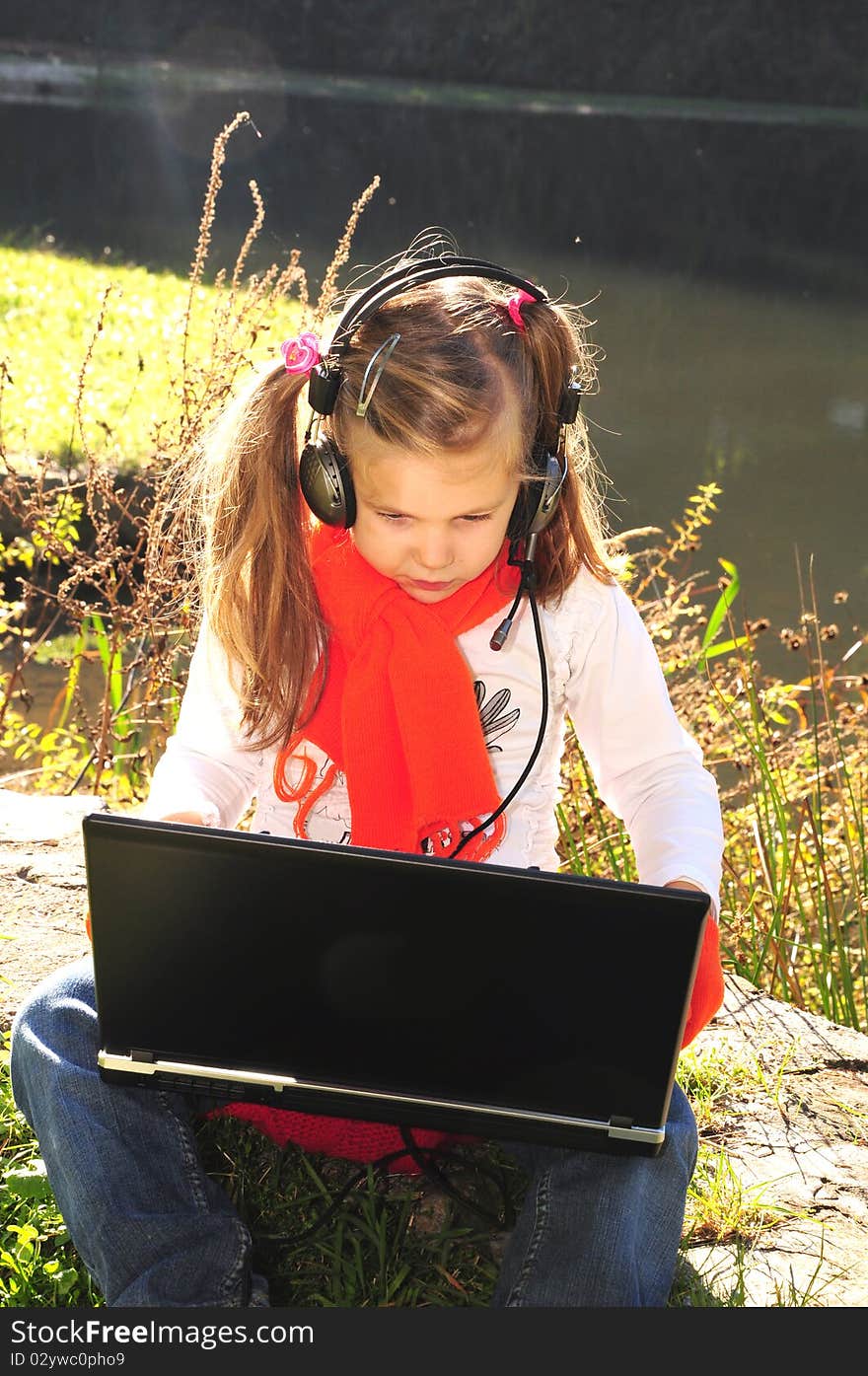 Little girl with a laptop next to the lake