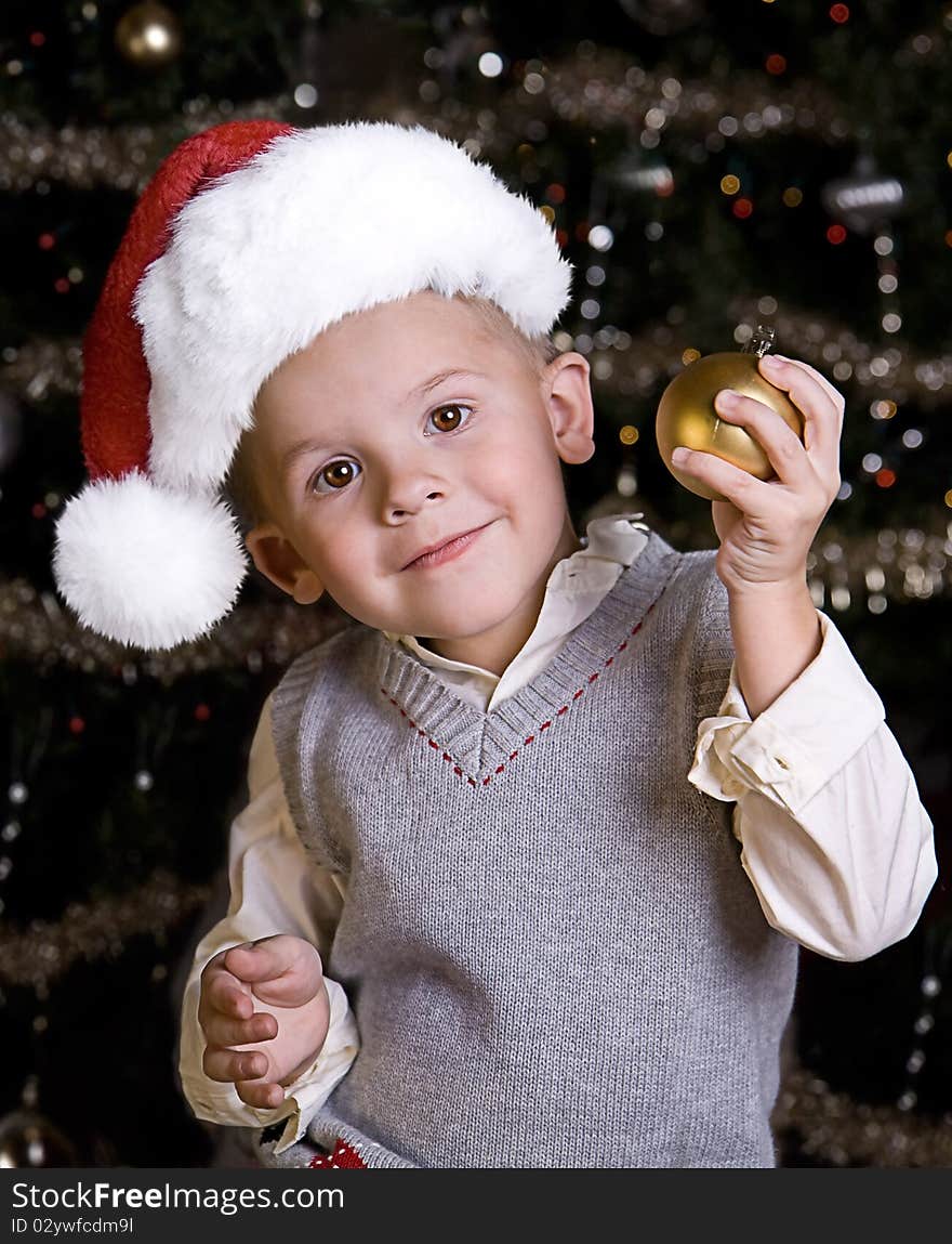 Adorable little boy wearing a Santa Hat in front of a Christmas tree. Adorable little boy wearing a Santa Hat in front of a Christmas tree