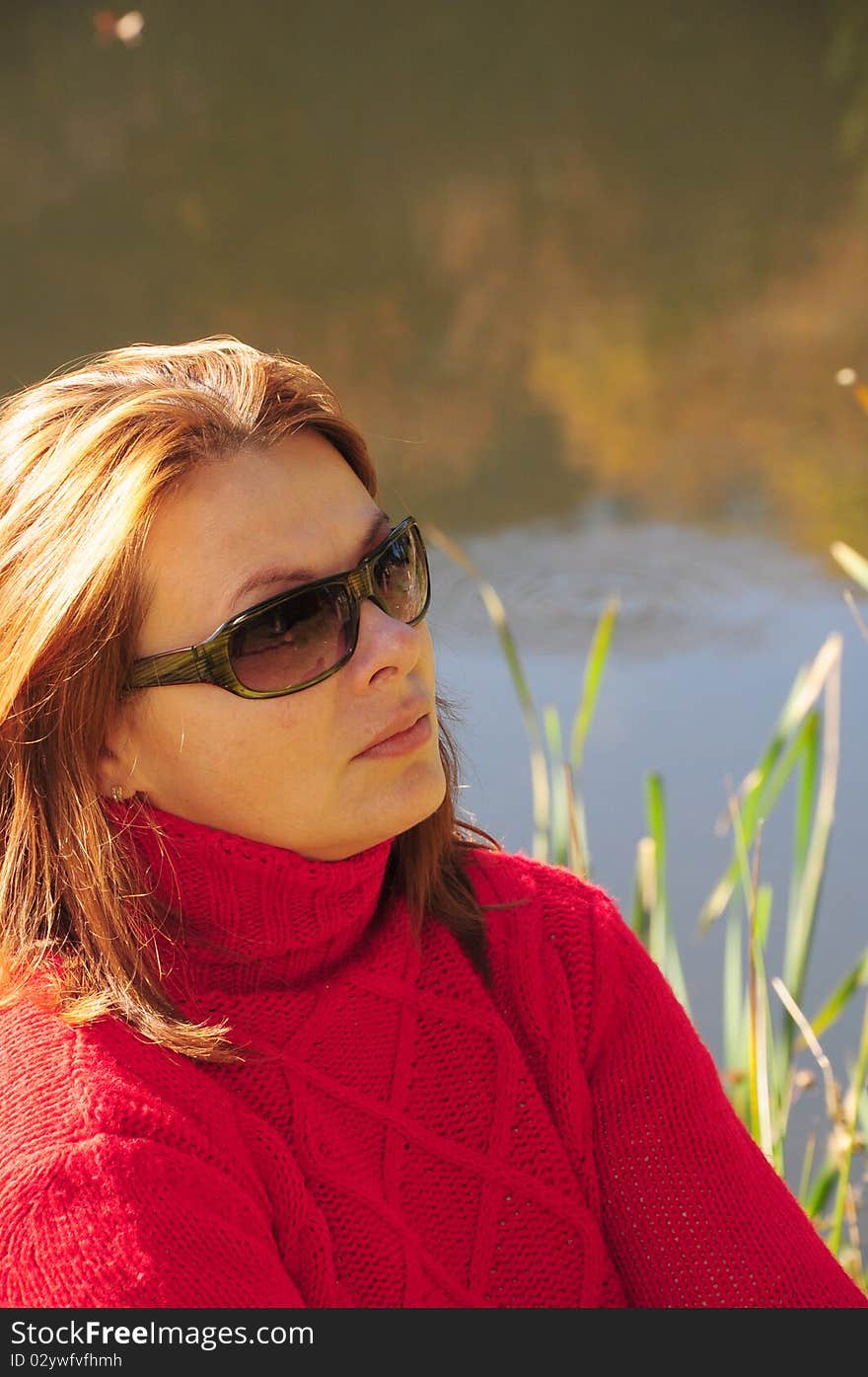 Portrait of young beautiful woman against lake in park.