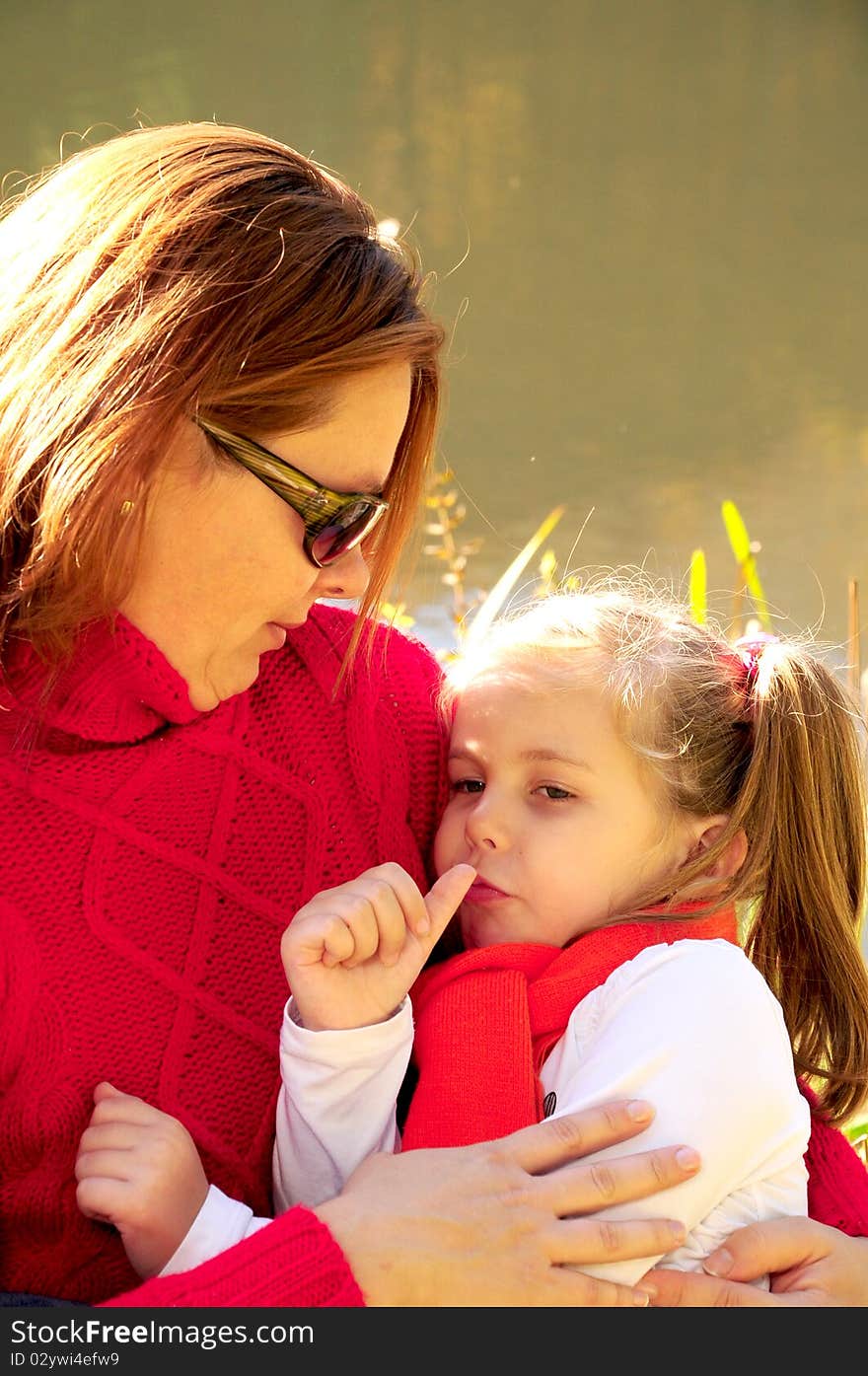 Mother and daughter sitting at the river bank