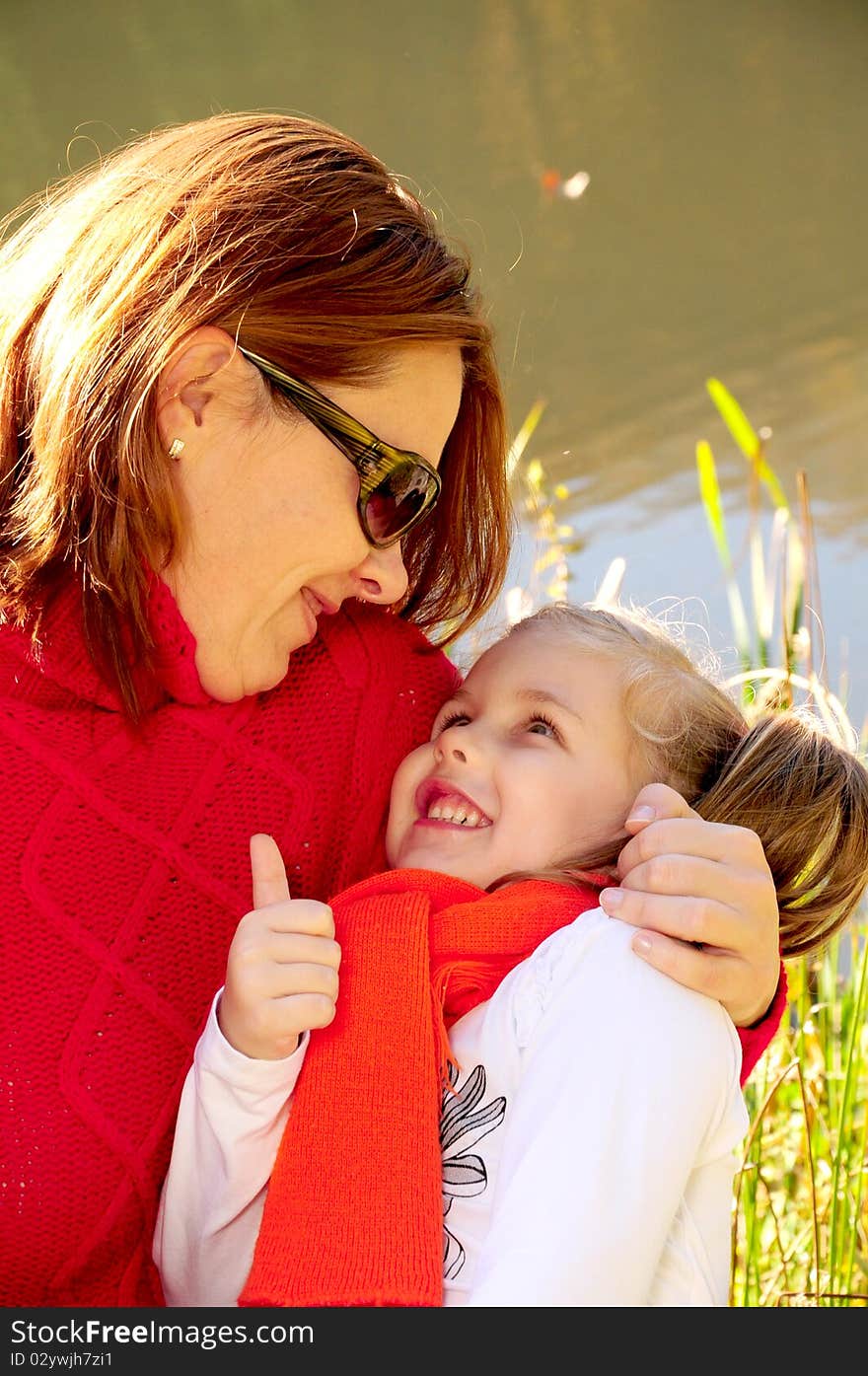 Mother and daughter sitting at the river bank