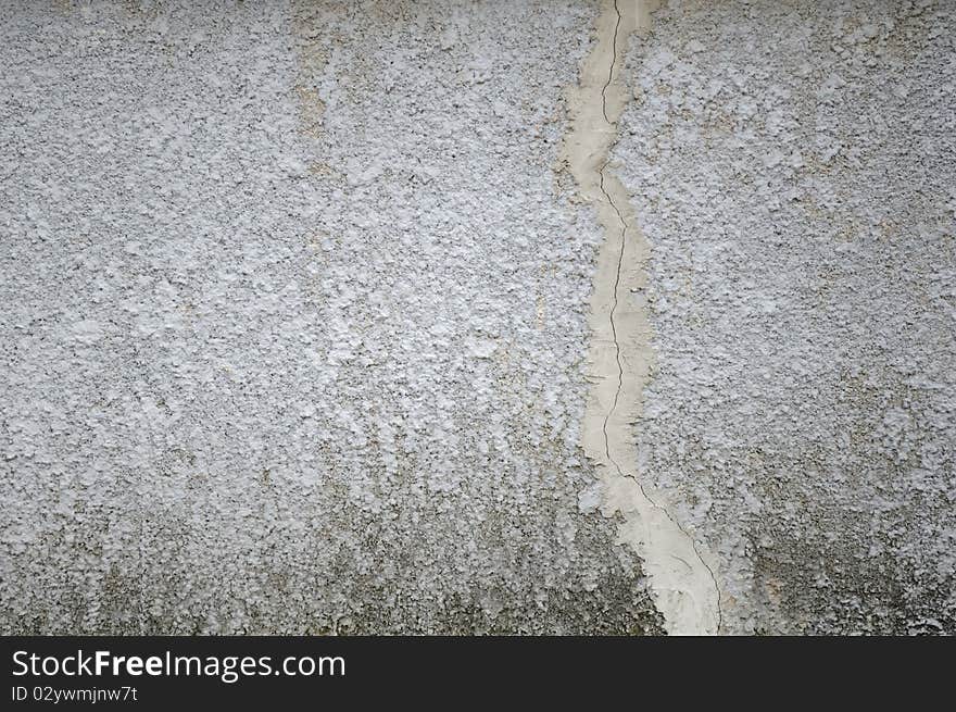 A grey concrete wall with a crack as a background. A grey concrete wall with a crack as a background