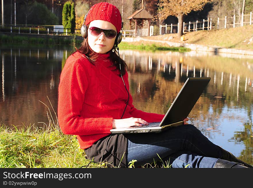 Young woman with laptop on the embankment.