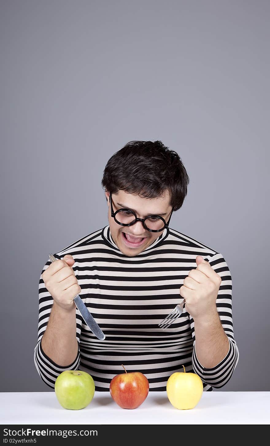 Funny boy try to eat apples. Studio shot.