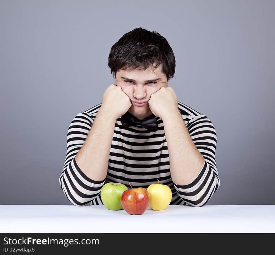 The young disappointed men with three apples. Studio shot.