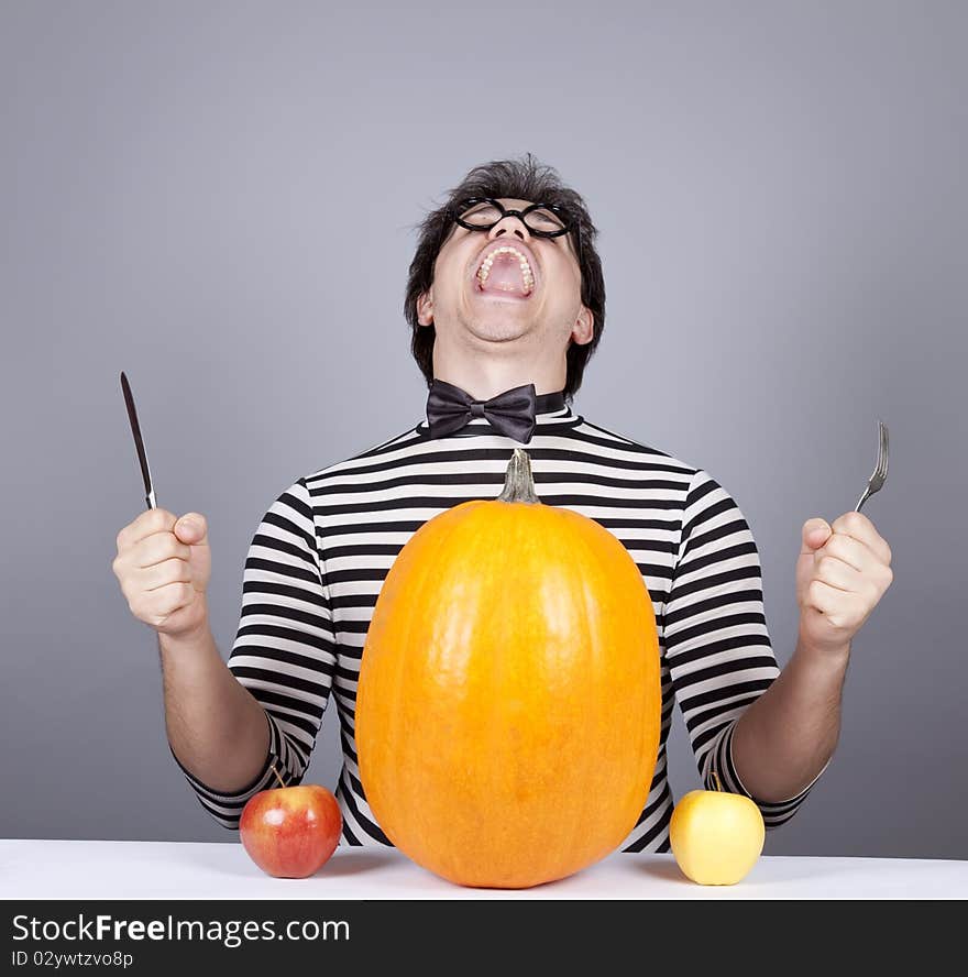 The young mad men try to eat apples and pumpkin.