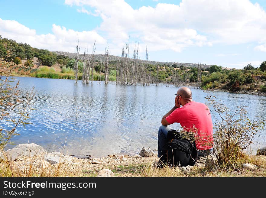 A man thinking by looking to sea / lake. A man thinking by looking to sea / lake