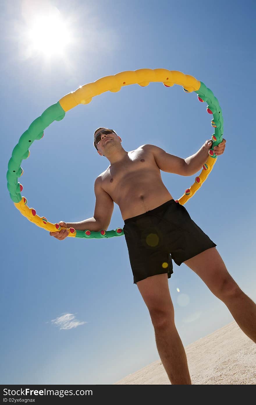 Young man Twirling Hula Hoop on the beach. Young man Twirling Hula Hoop on the beach