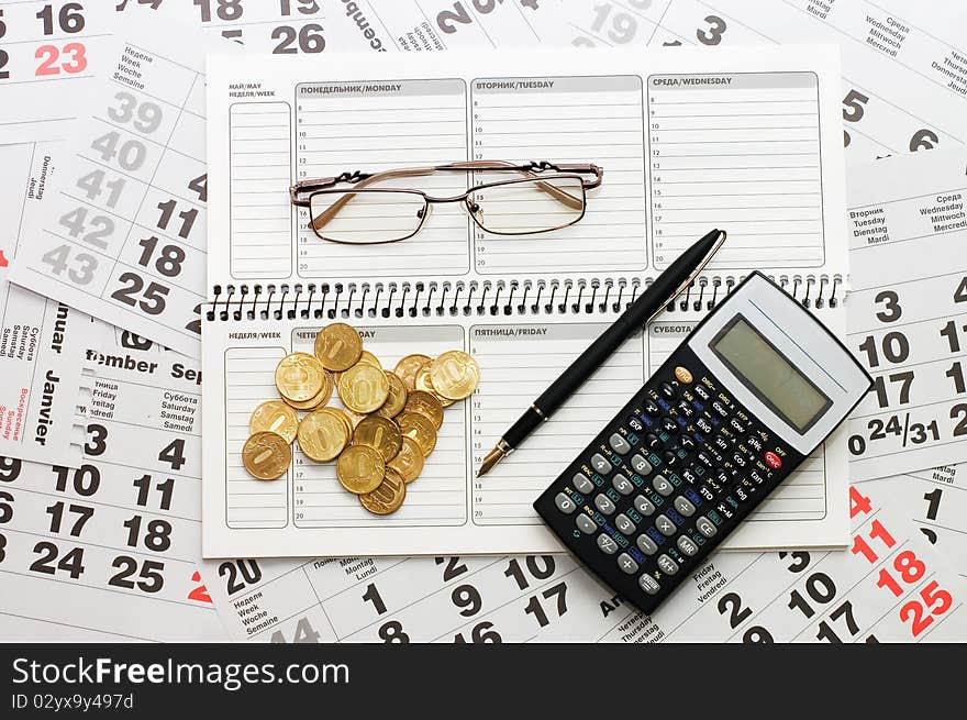 Sheets of a calendar with coins and a notebook still life