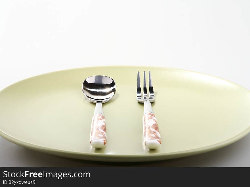 Fork and spoon on green plate