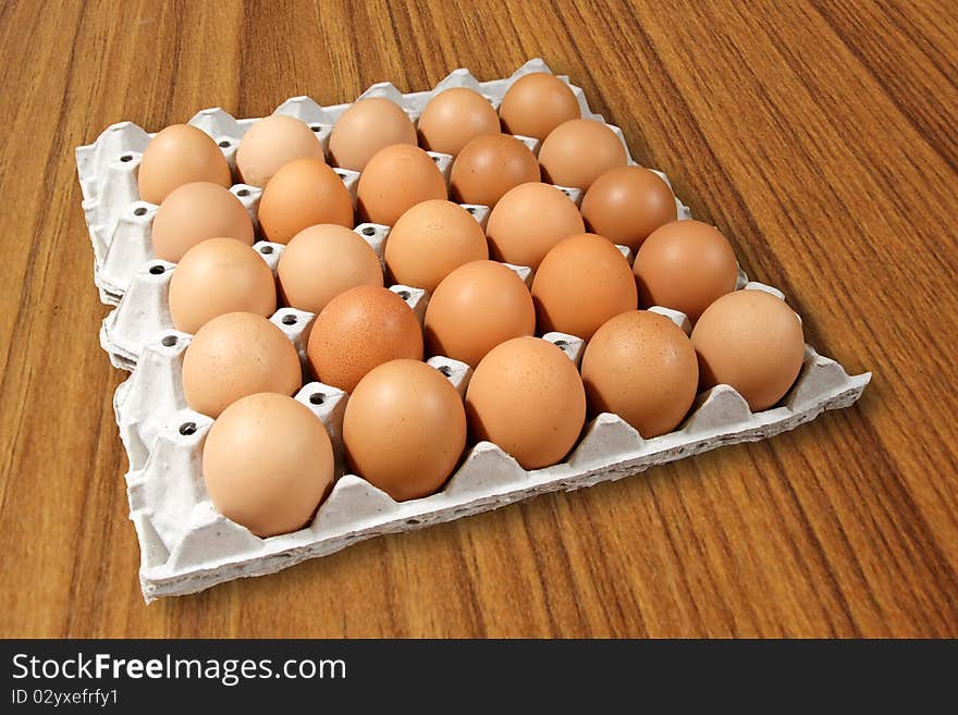 Carton of fresh brown eggs on Wood background