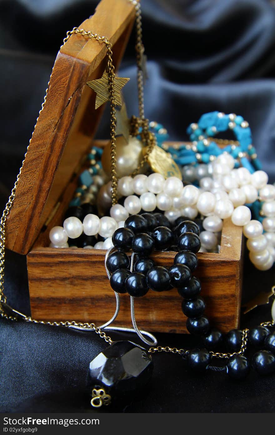 Jewelry pearls in a wooden chest on a black background