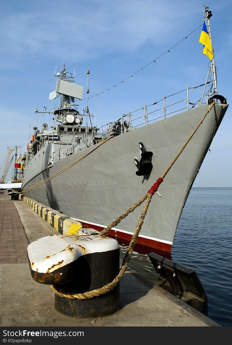 Military ship in the port against yallow cranes and blue sky