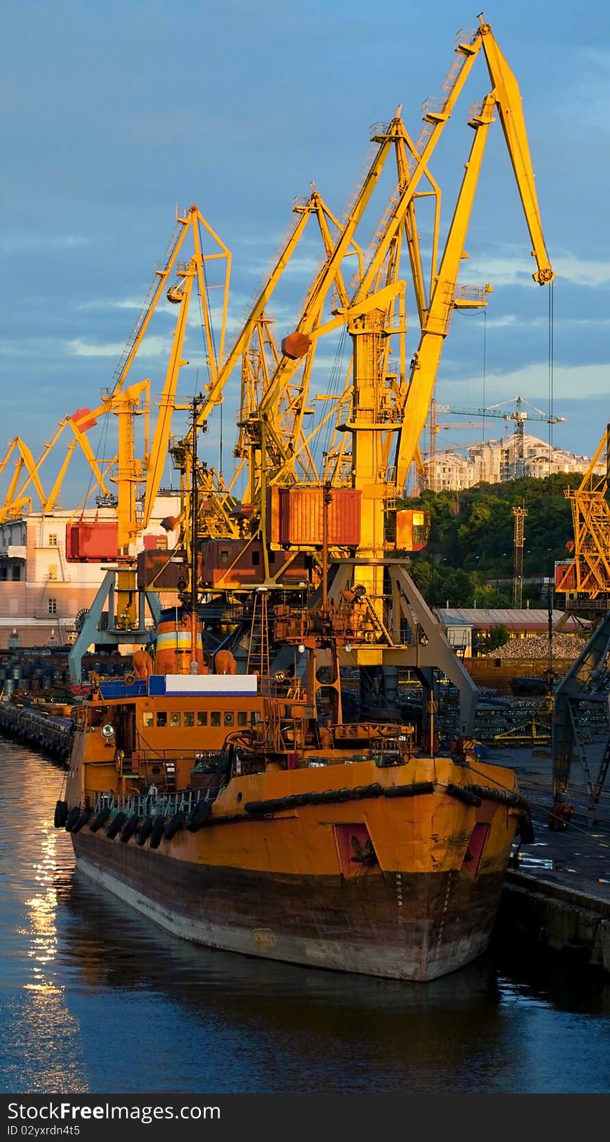 Ship in the port against big yellow cranes ane blue sky with clouds