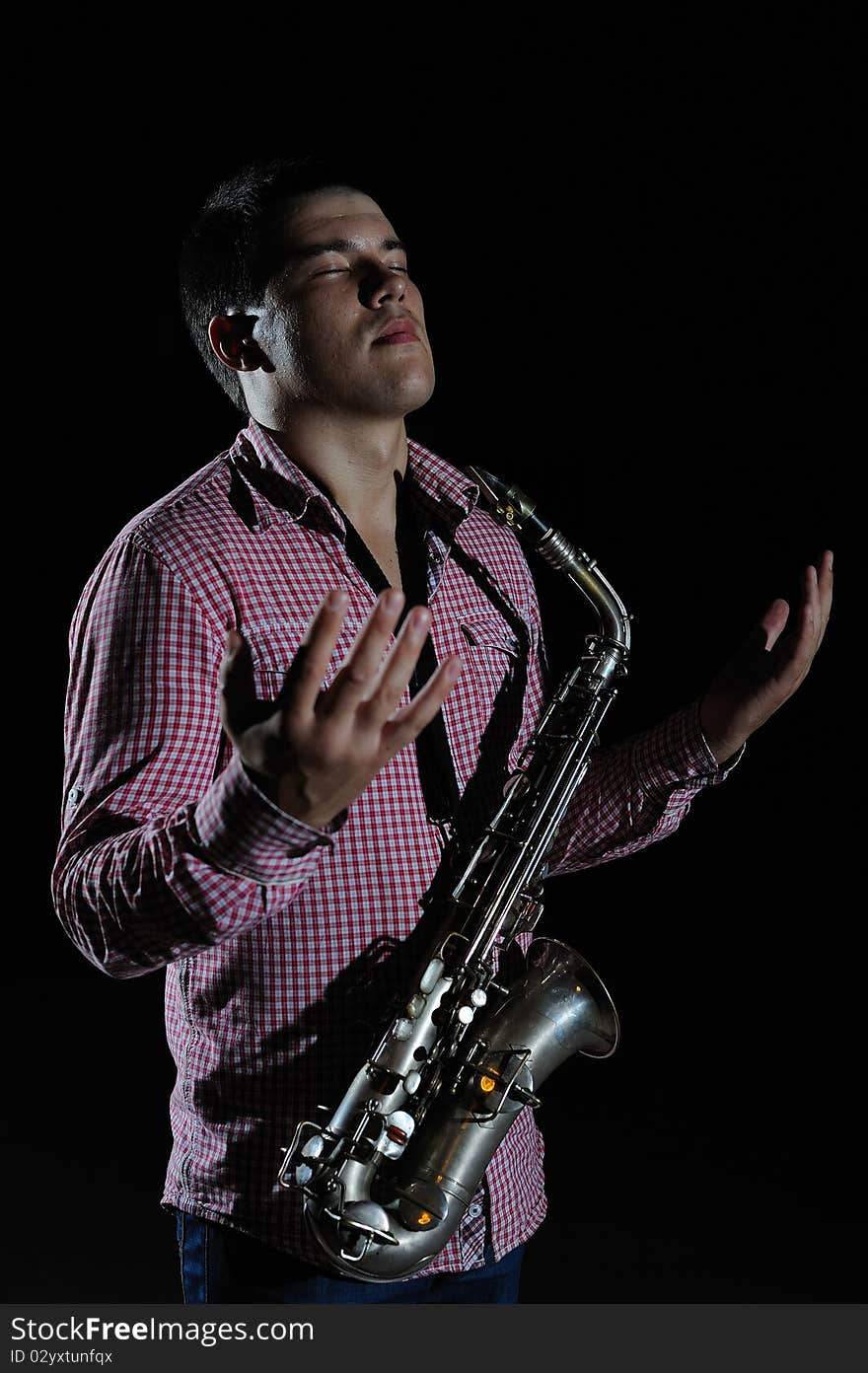 Young handsome man playing music on saxophone