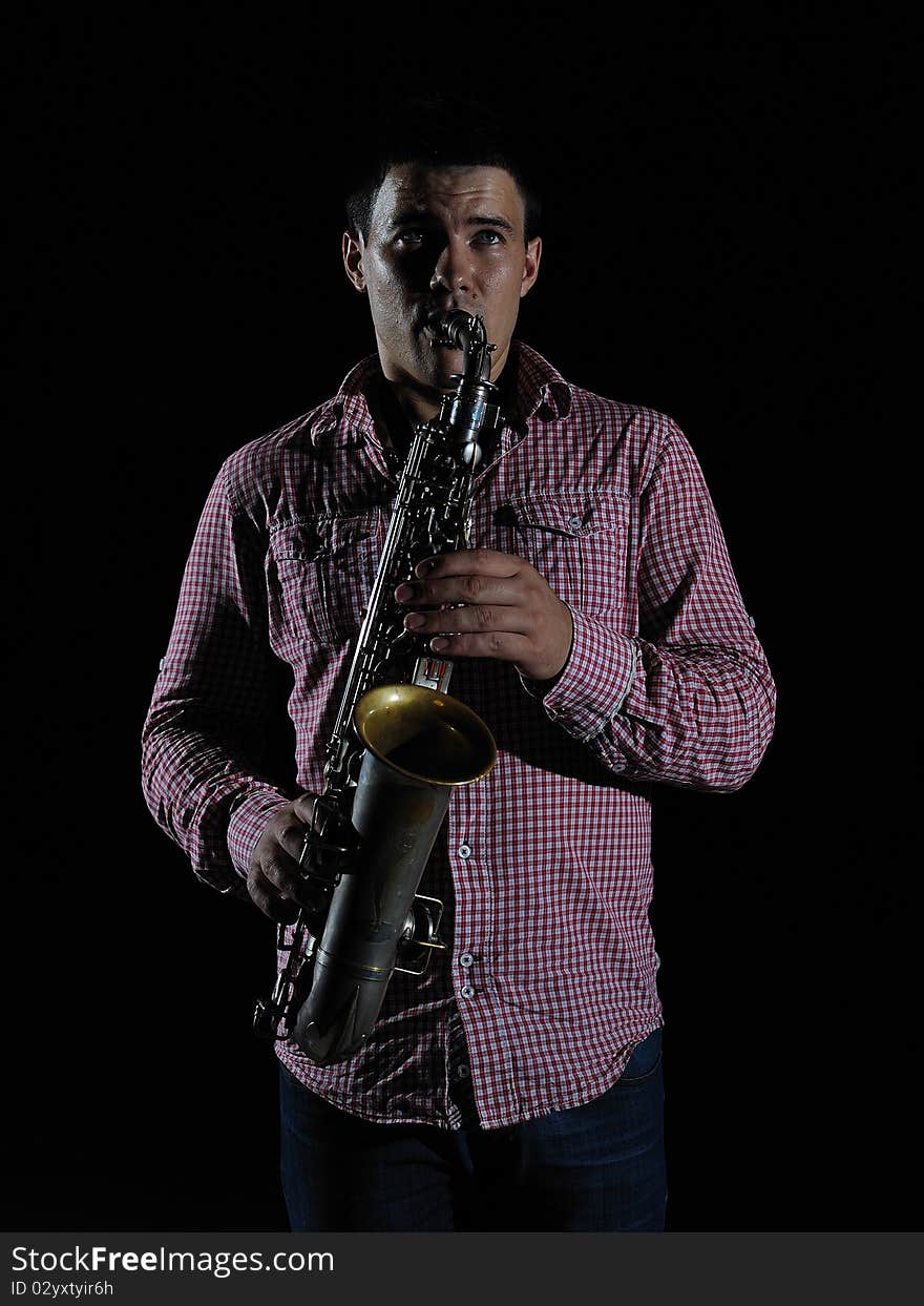 Young handsome man playing music on saxophone