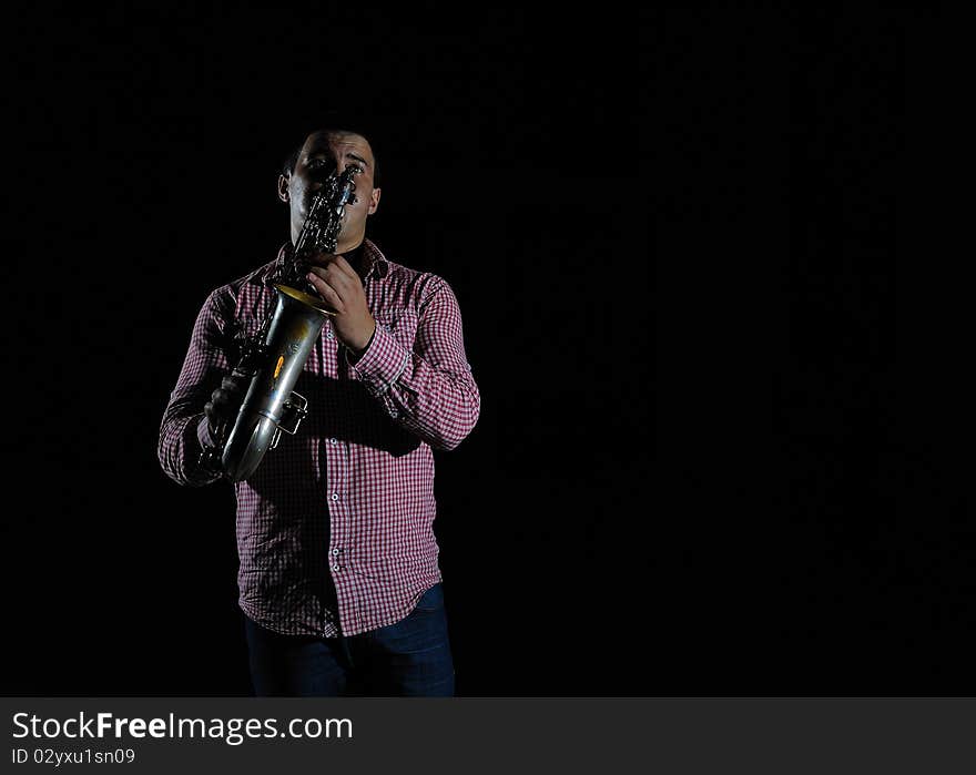 Young handsome man playing music on saxophone