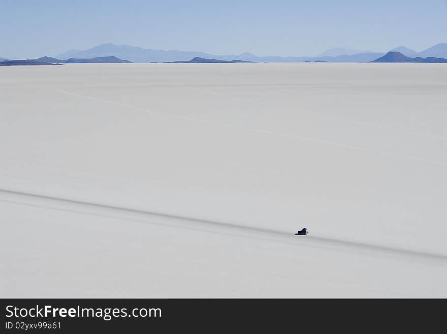 Jeep in Tunupa salt flats, with volcanic hills in the distance