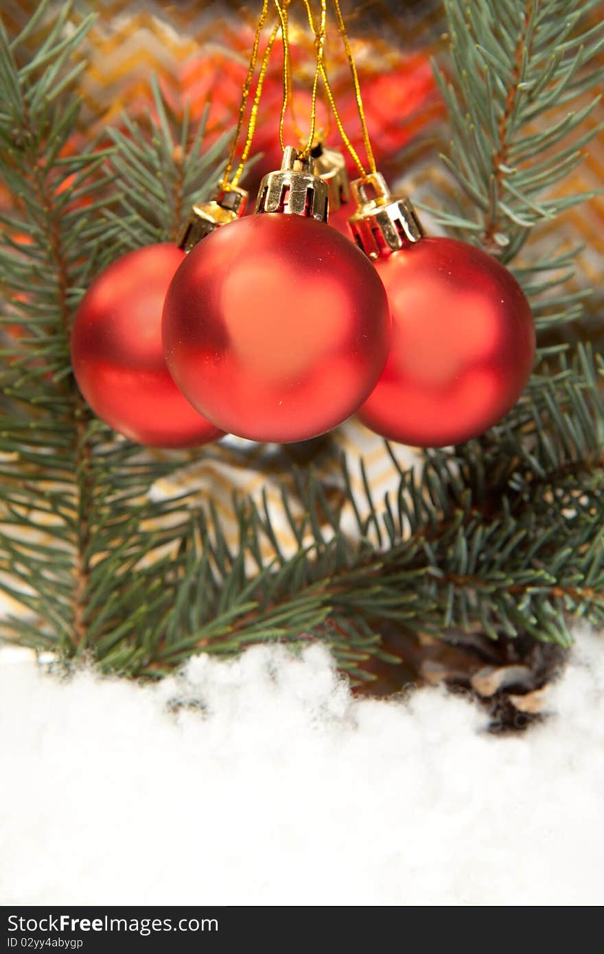 Three red christmas balls with christmas tree on the gold background