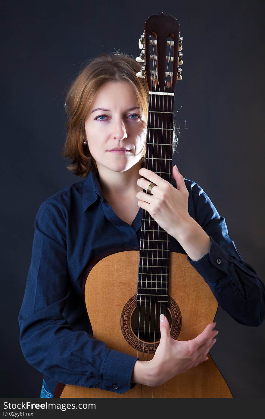 Portrait of the girl with a guitar on a black background