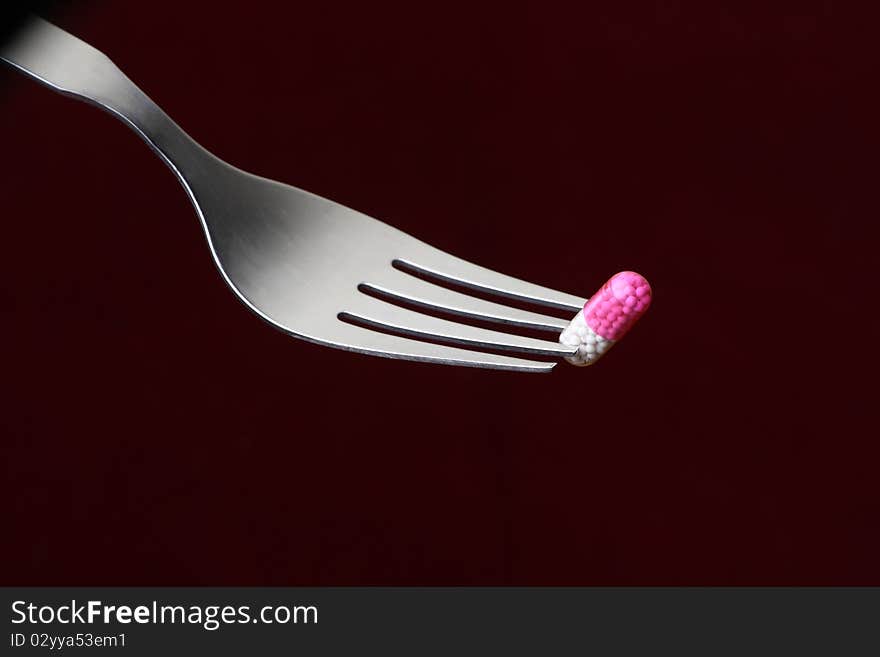 Conceptual shot of a capsule on a fork in a dark background