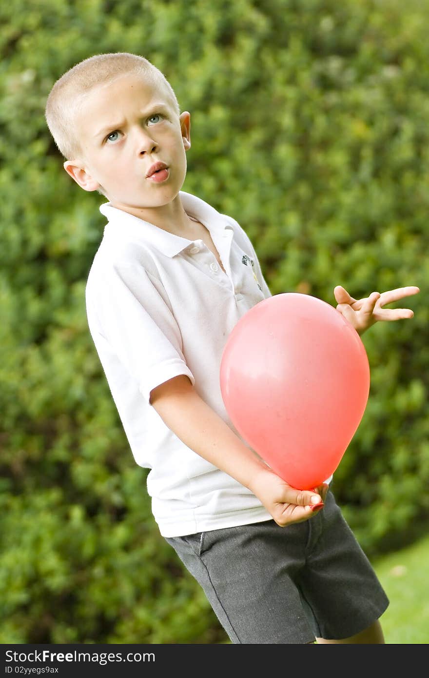 Young six year old boy holding a red balloon. Young six year old boy holding a red balloon