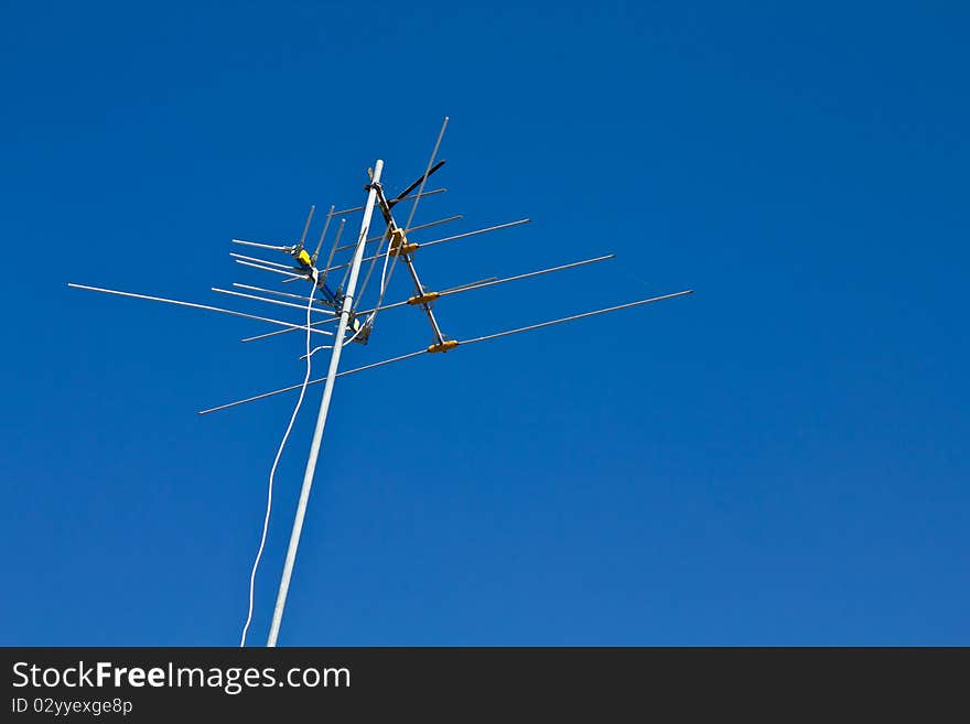 An antenna old style on the top of the building with bright blue sky. An antenna old style on the top of the building with bright blue sky