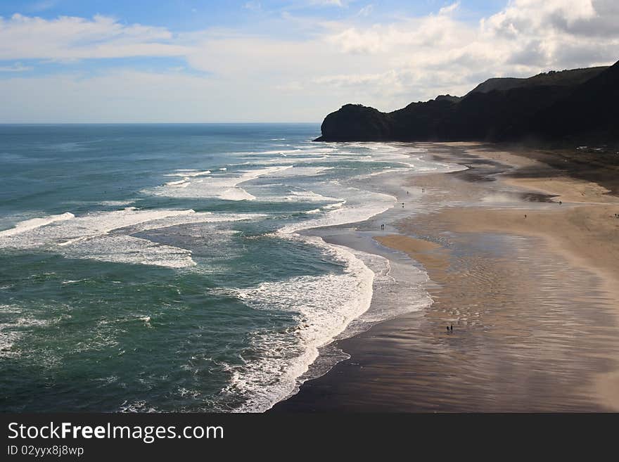 People walking on Beach with surf waves rolling in, piha, new zealand. People walking on Beach with surf waves rolling in, piha, new zealand