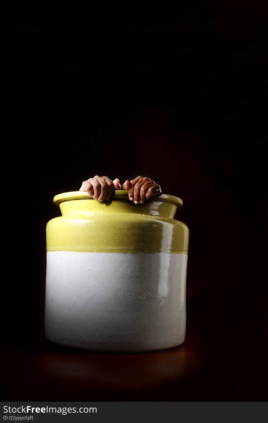 Surreal image of a man hiding in an old clay pot in darkness. Surreal image of a man hiding in an old clay pot in darkness