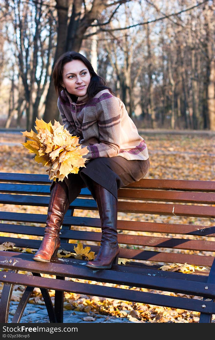 Beautiful young woman on a bench in autumn