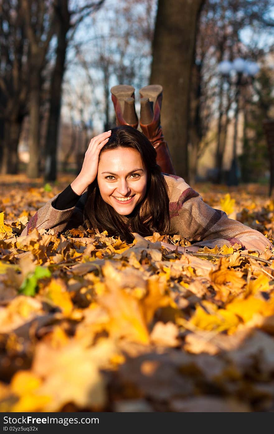 Beautiful young woman lying in autumn leaves