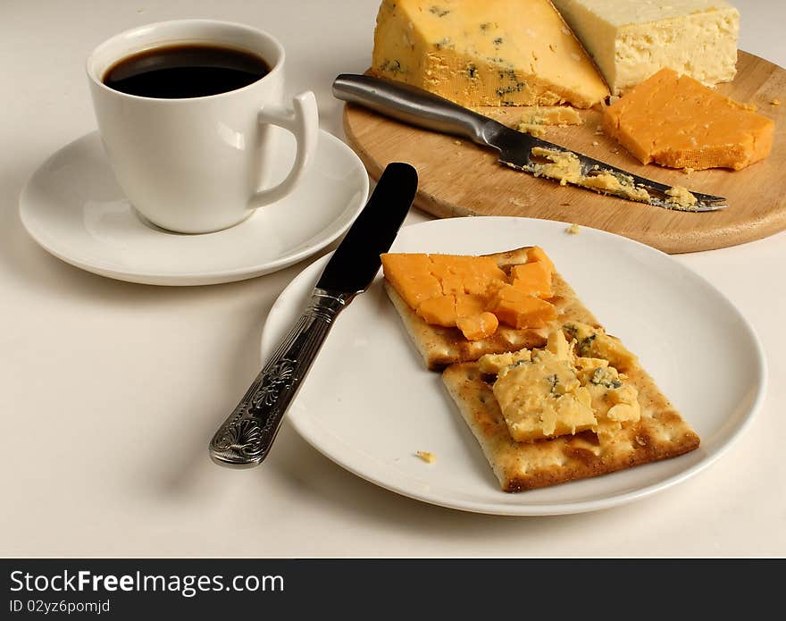 Cheese and crackers with a cup of black coffee and a cheese board with assorted cheeses. Cheese and crackers with a cup of black coffee and a cheese board with assorted cheeses