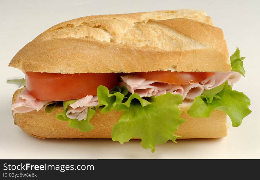 A sandwich made with fresh French Roll, ham, lettice and tomato. A sandwich made with fresh French Roll, ham, lettice and tomato