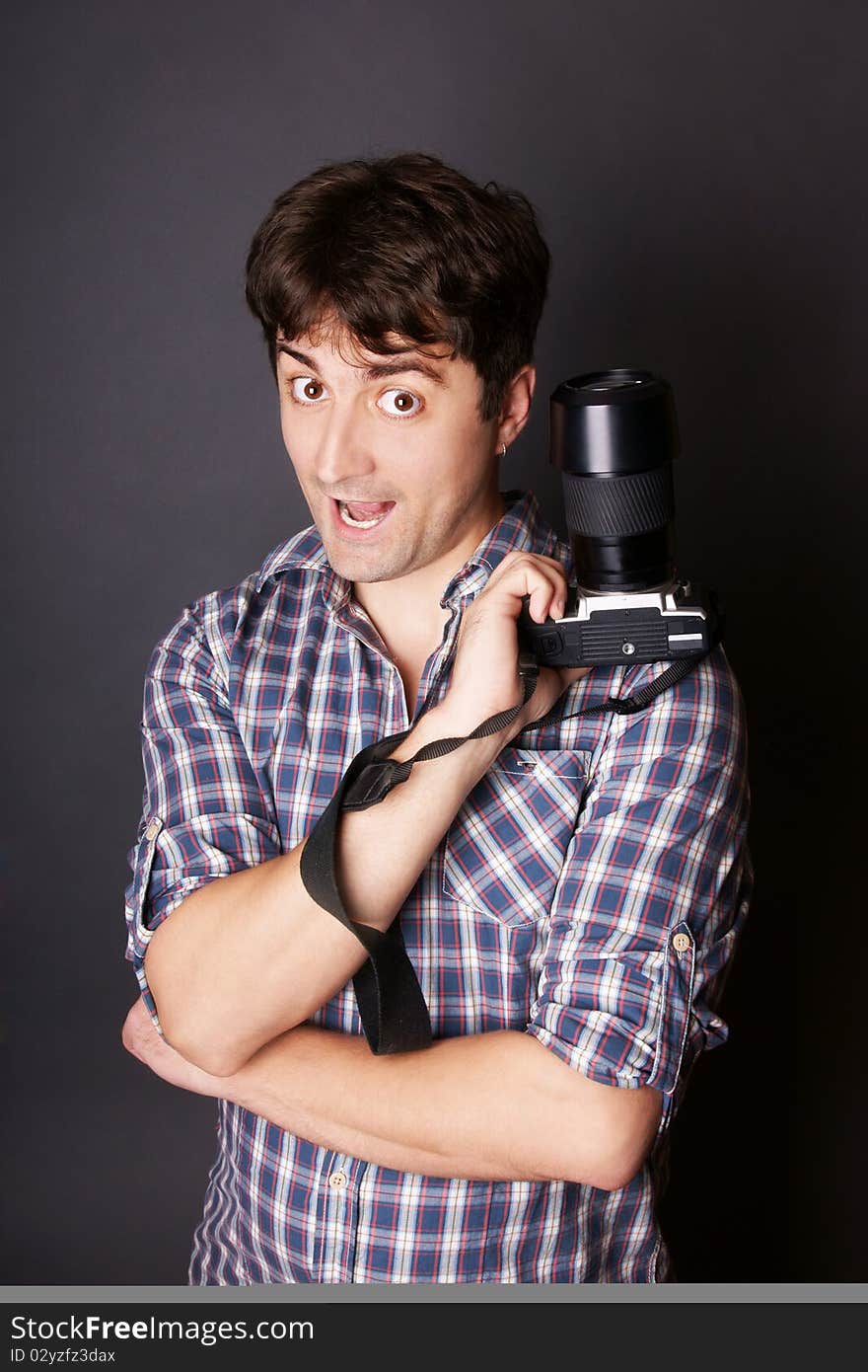 Portrait of young attractive grimacing man with camera, studio shot