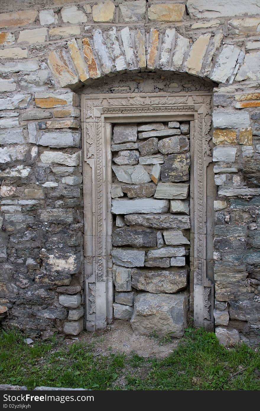 Old lithoidal wall with a doorway in form arch, heaped up by stones. Old lithoidal wall with a doorway in form arch, heaped up by stones