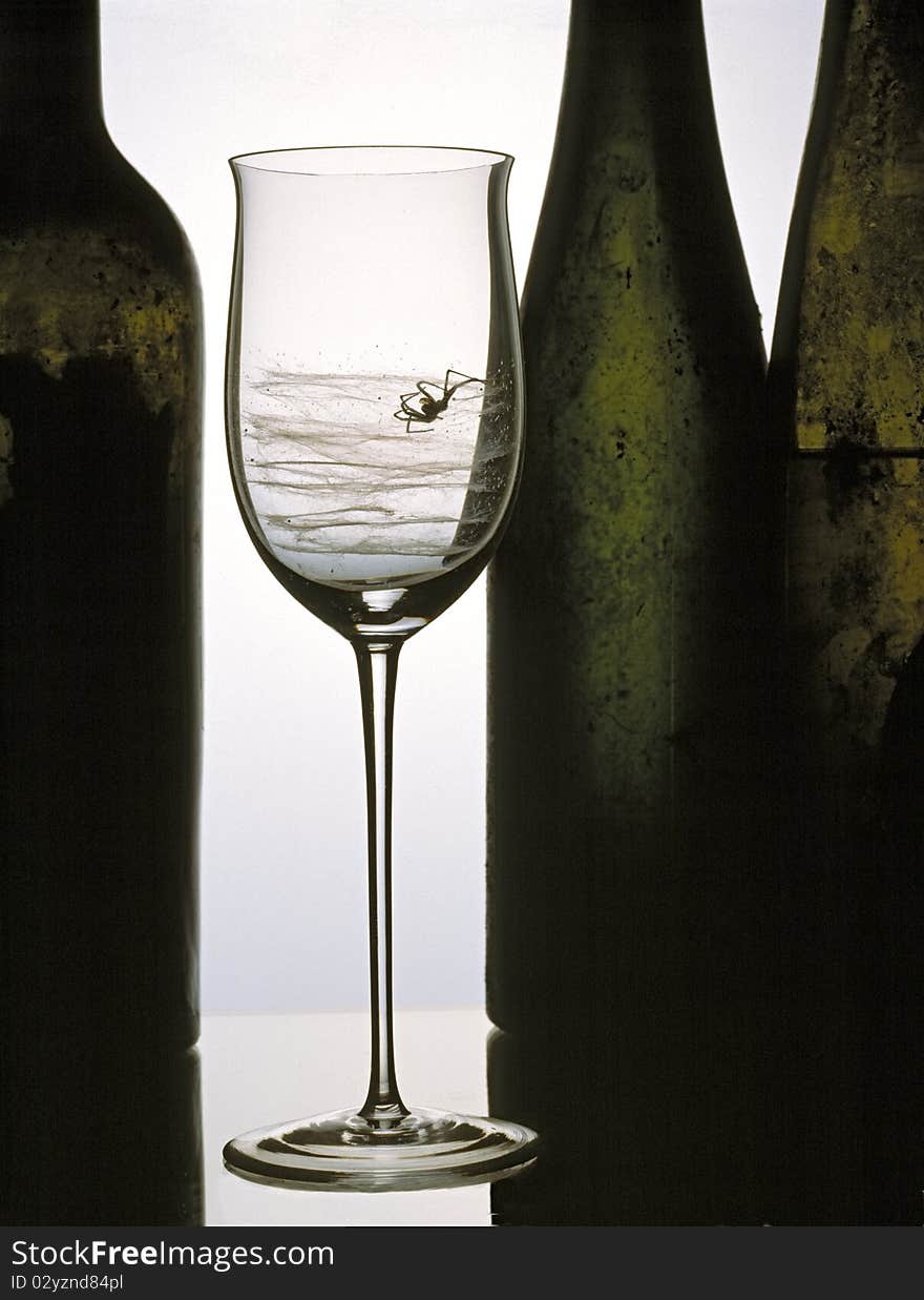 Spider with web in a glass and old bottles in the background