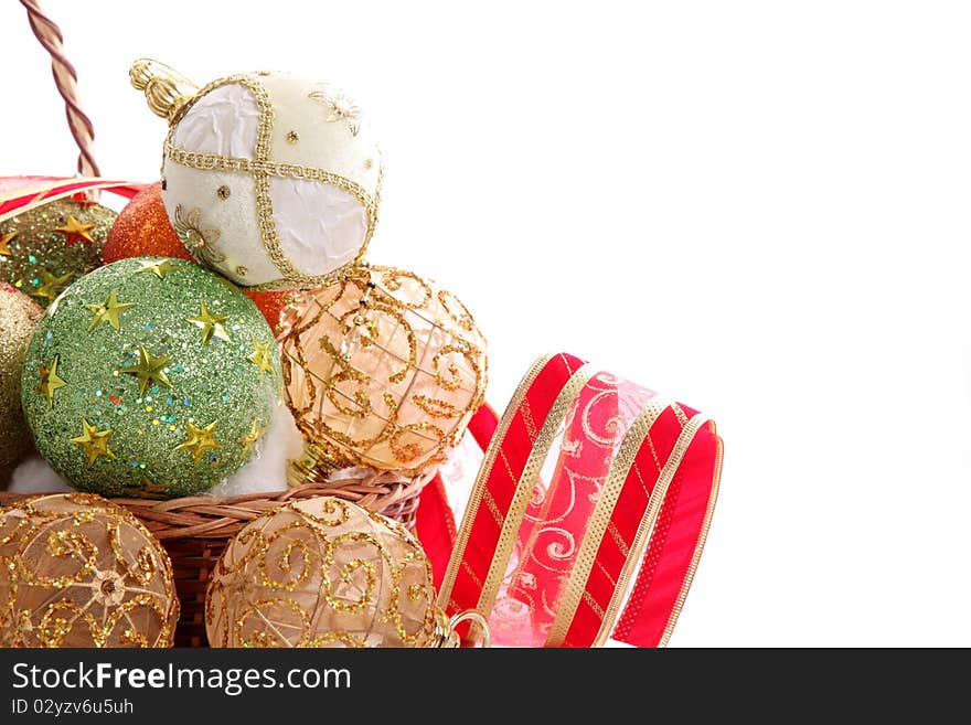 Green,gold,white christmas balls in basket with red ribbon over blank background.