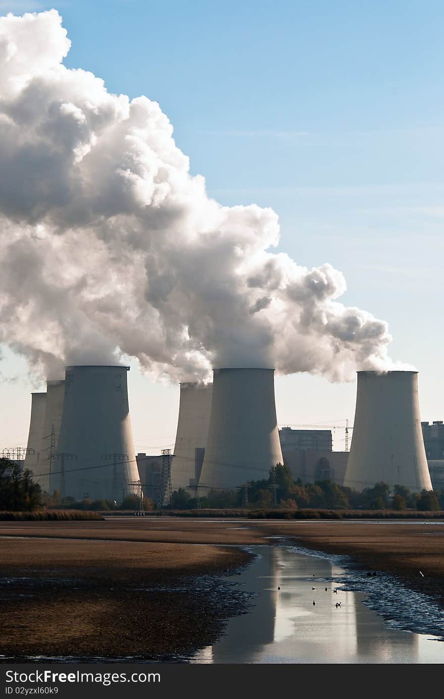 Cooling towers of a power plant with steam clouds and sky. Cooling towers of a power plant with steam clouds and sky