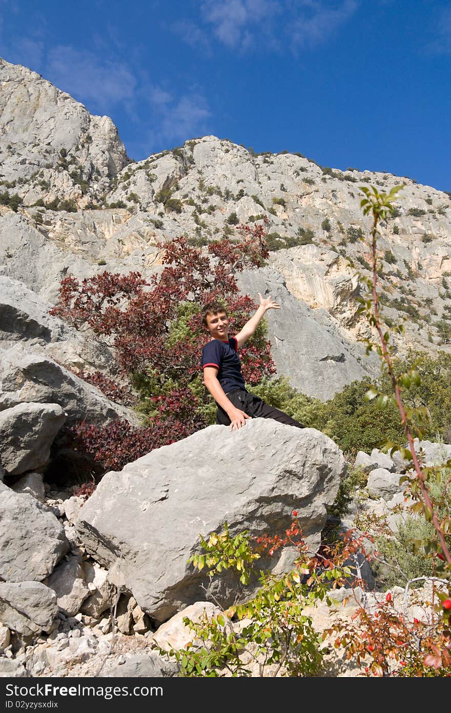 A teenager sits on a stone.