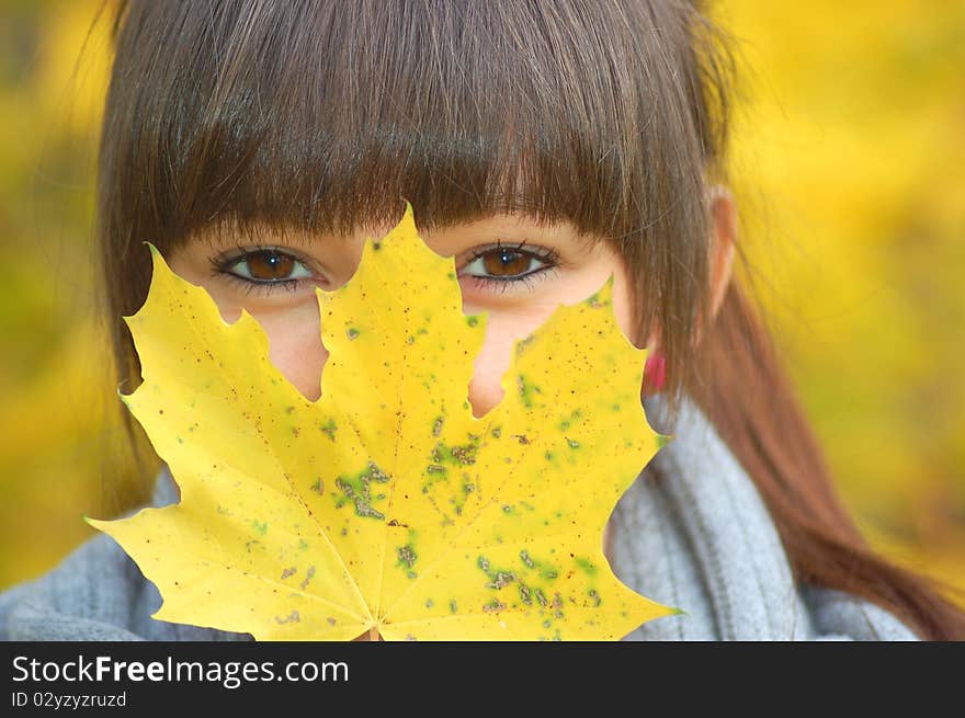 A girl hidden behind maple autumn mask. A girl hidden behind maple autumn mask