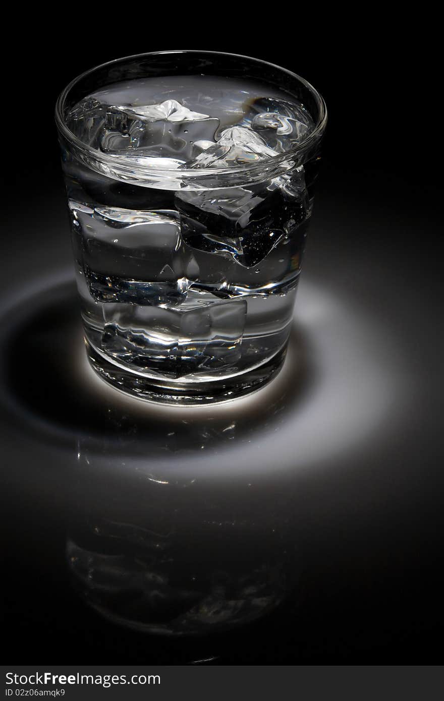 Glass of ice water in spotlight lighting. Glass of ice water in spotlight lighting.