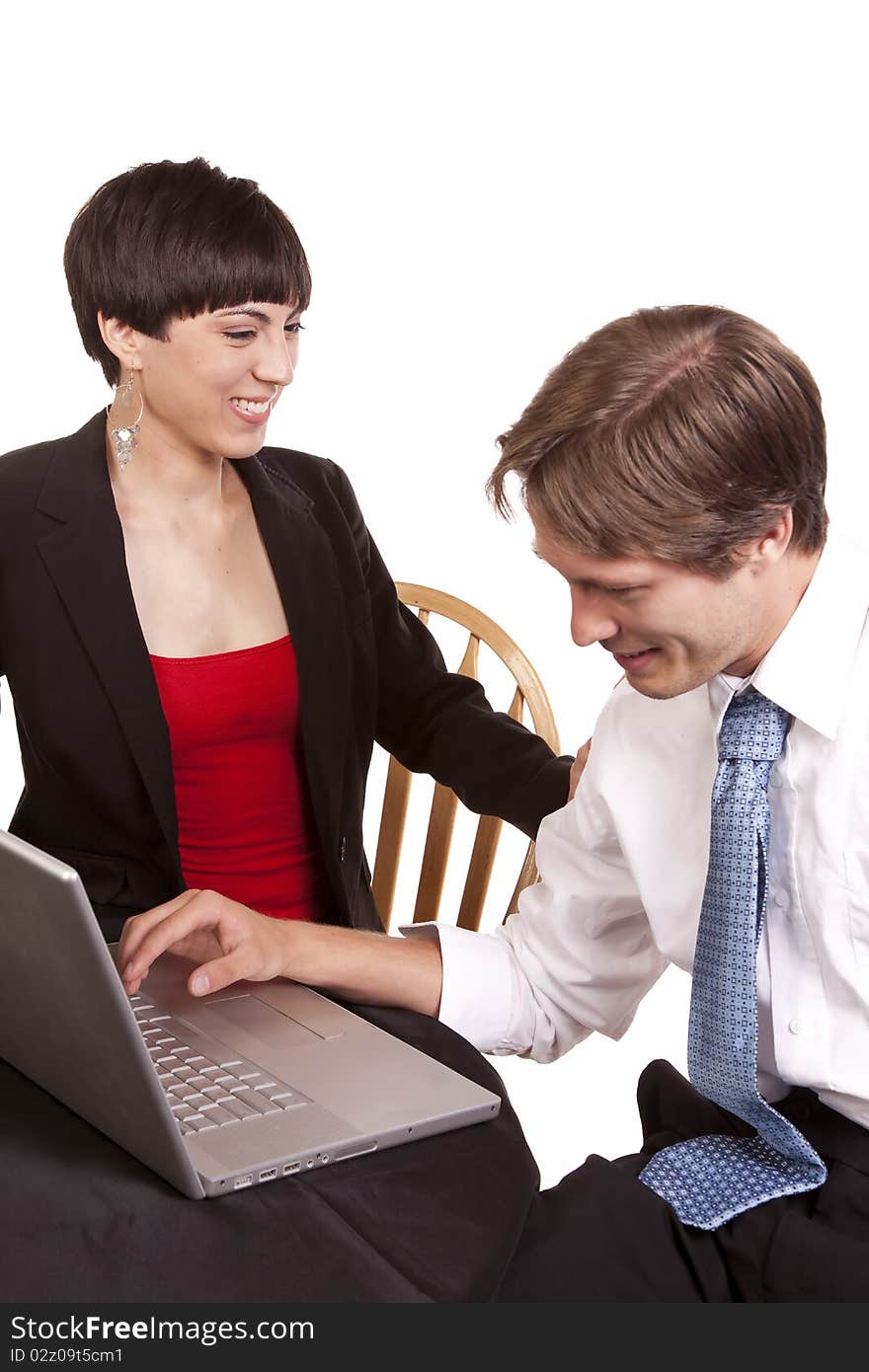 A business woman and man working on the computer laughing together.